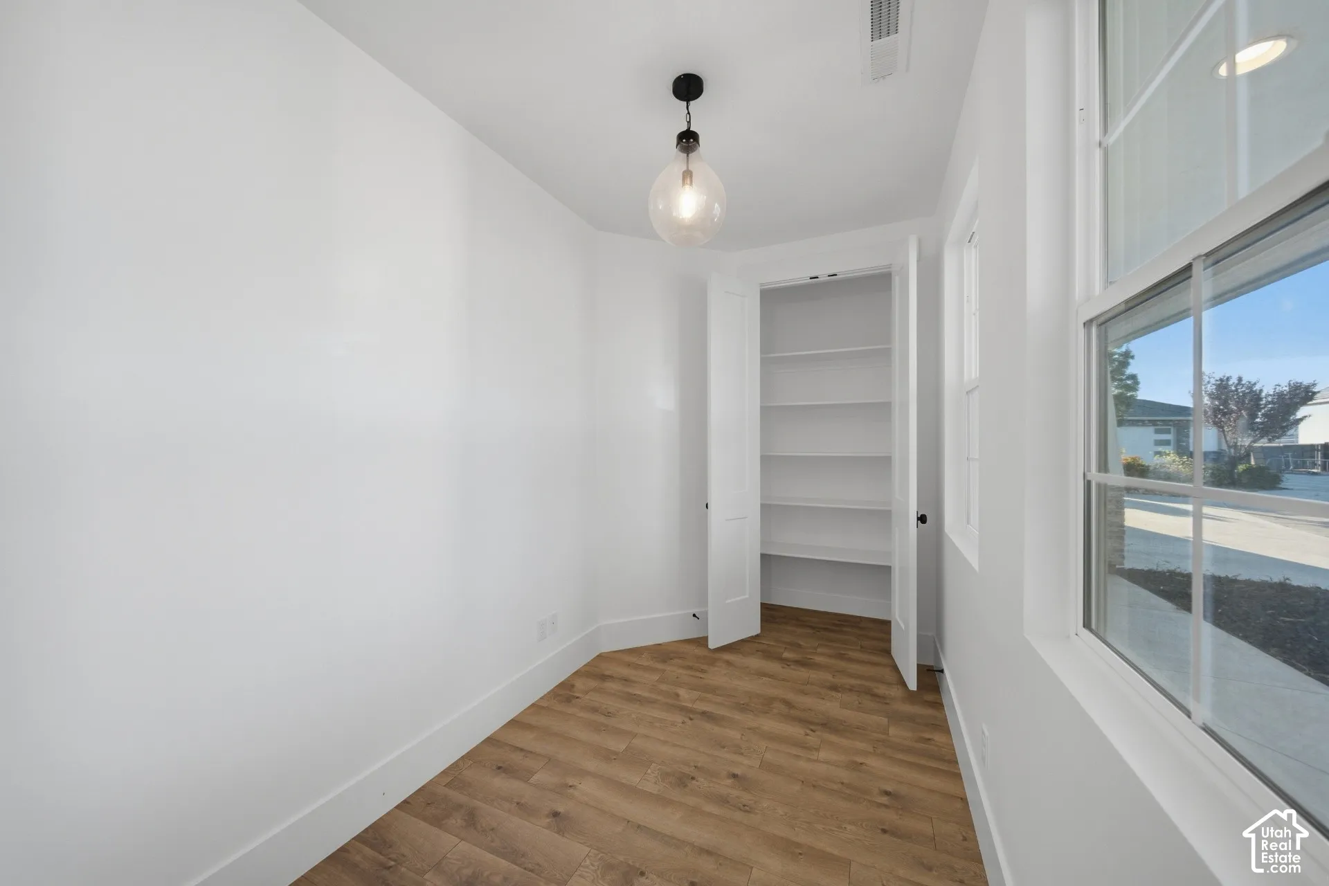 Wood-finish flooring, white walls, and a multi-pane window