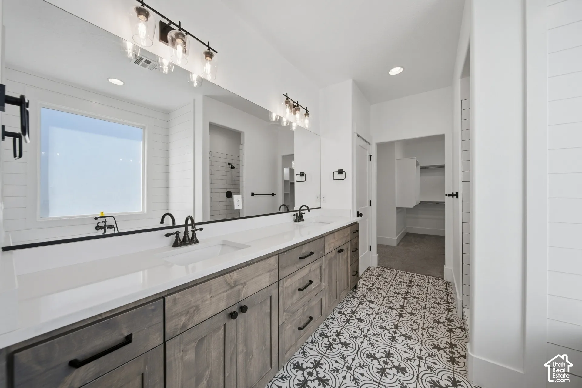 Dual vanity with white countertops, wood-finish cabinetry, and black fixtures