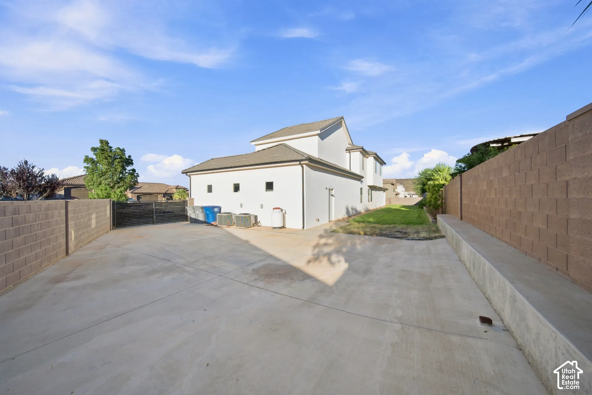 Spacious concrete area with block wall perimeter, partial grass landscaping, and multi-story exterior architecture