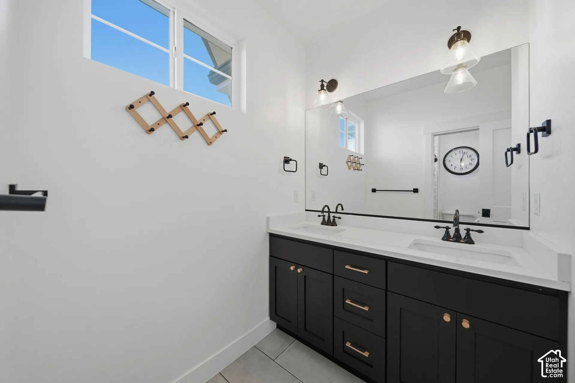 Dual vanity with black cabinetry and bronze hardware, featuring a large wall-mounted mirror and two sets of sconce lighting