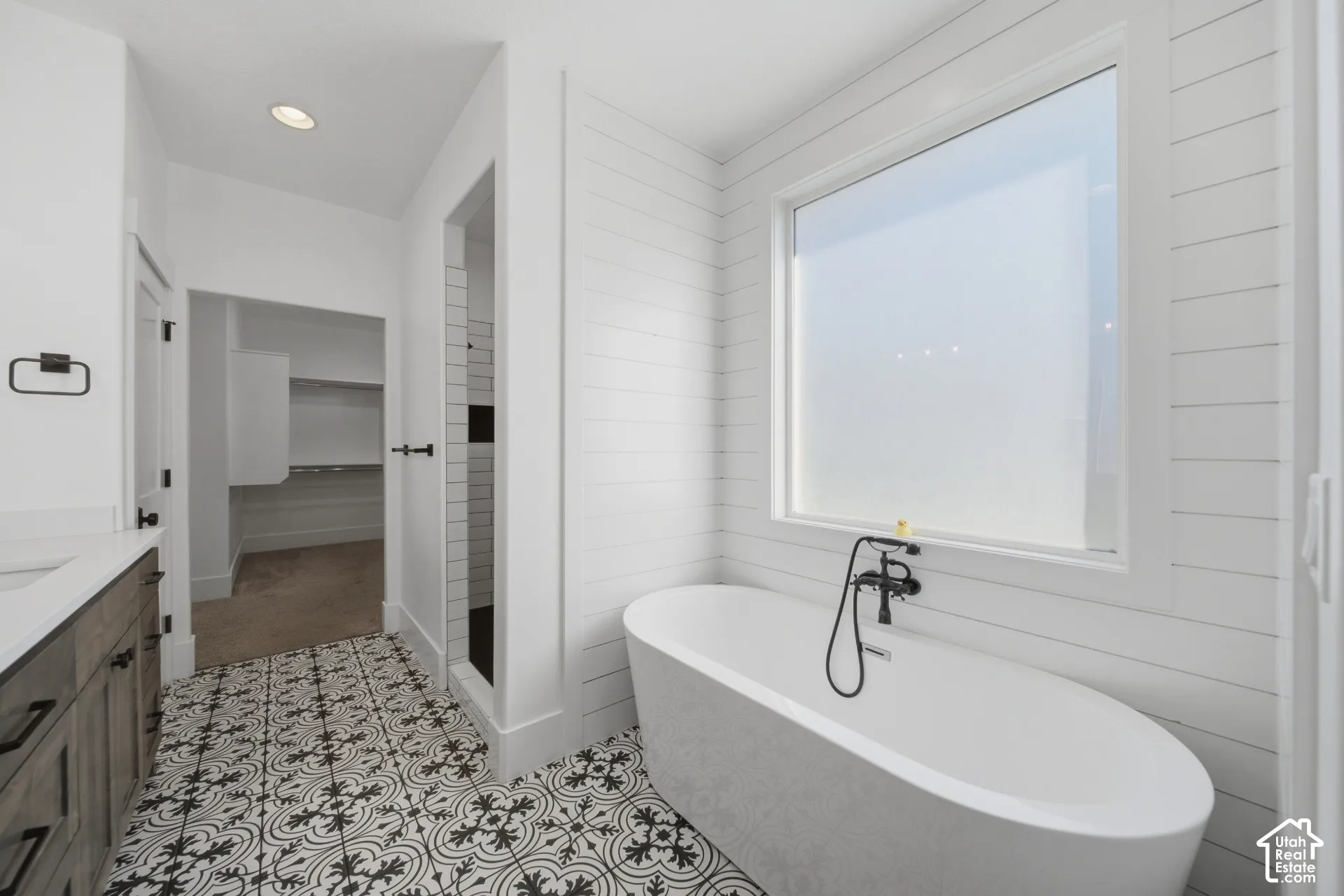 Freestanding soaking tub with a wall-mounted faucet, shiplap wall accent, patterned floor tile, and a walk-in shower with subway tile
