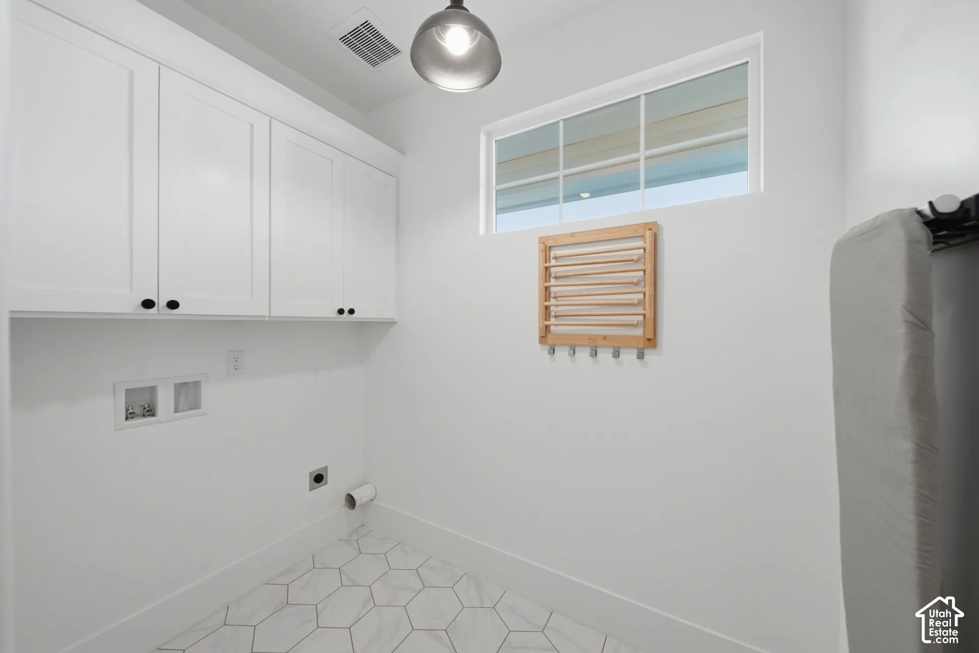 White shaker-style cabinetry with black hardware, hexagonal floor tiling, and a transom window