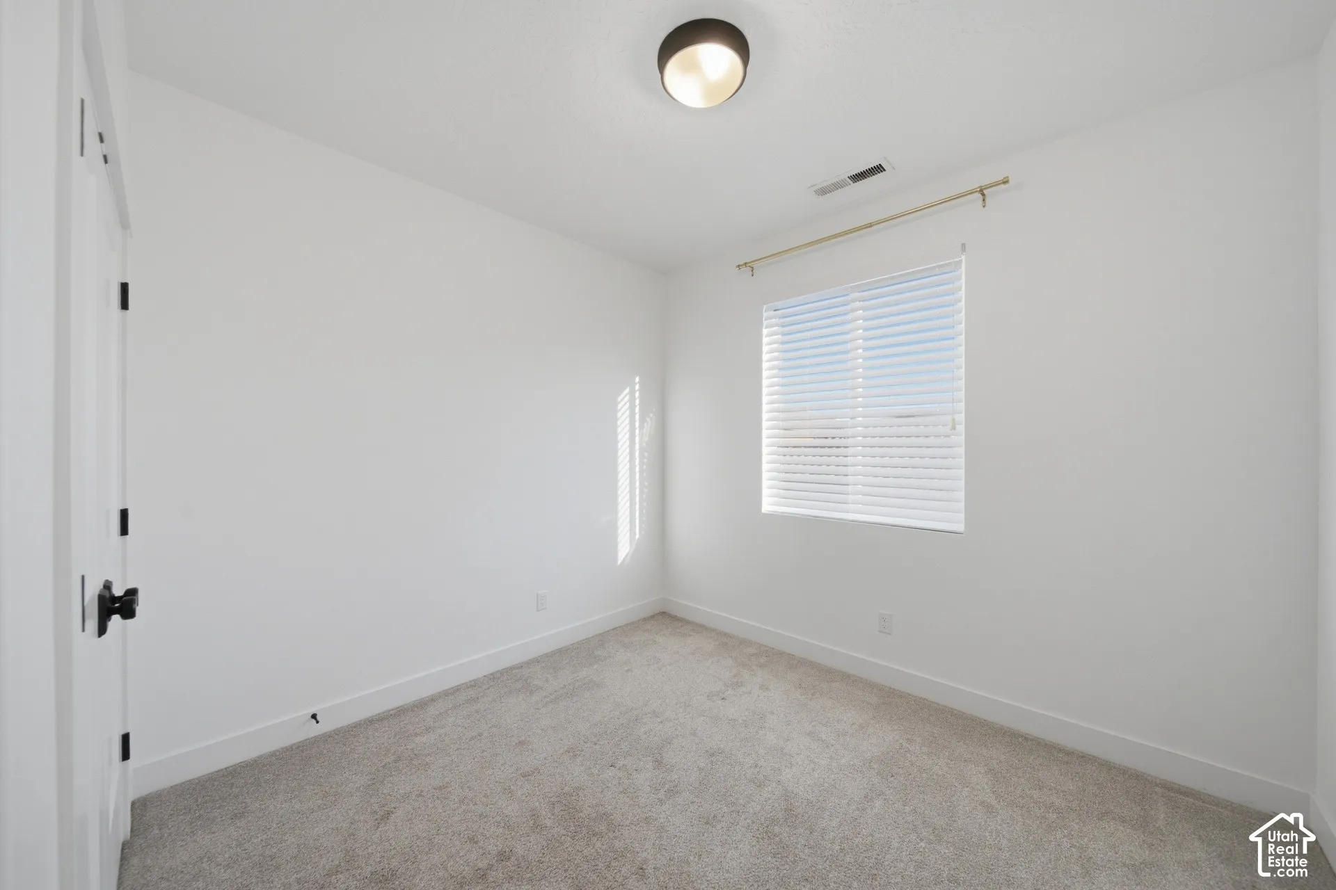Plush carpet flooring, white walls, and a window with blinds