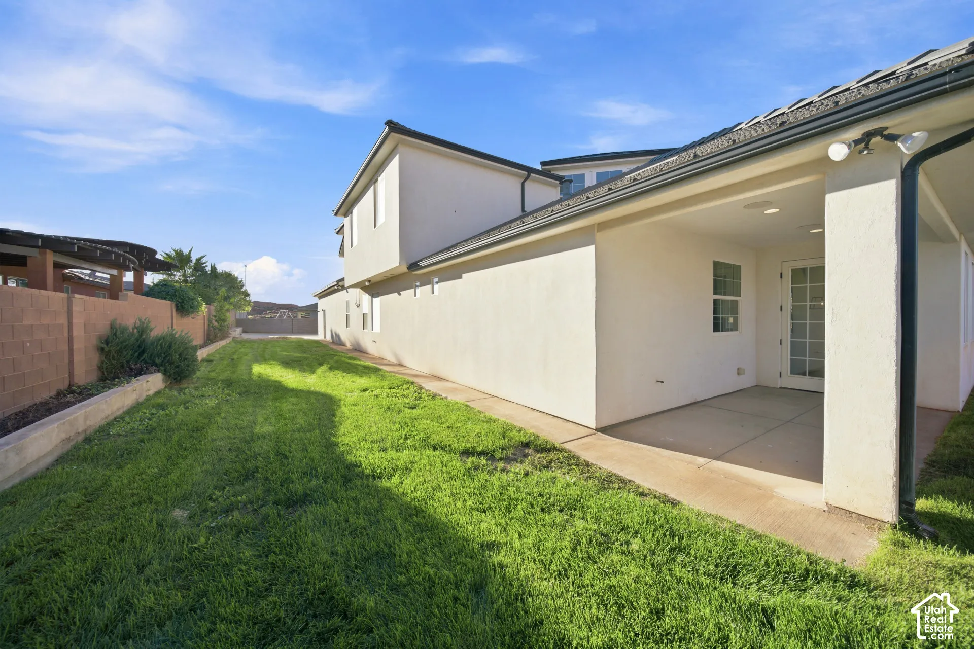 Expansive grass area with a covered patio and concrete flooring