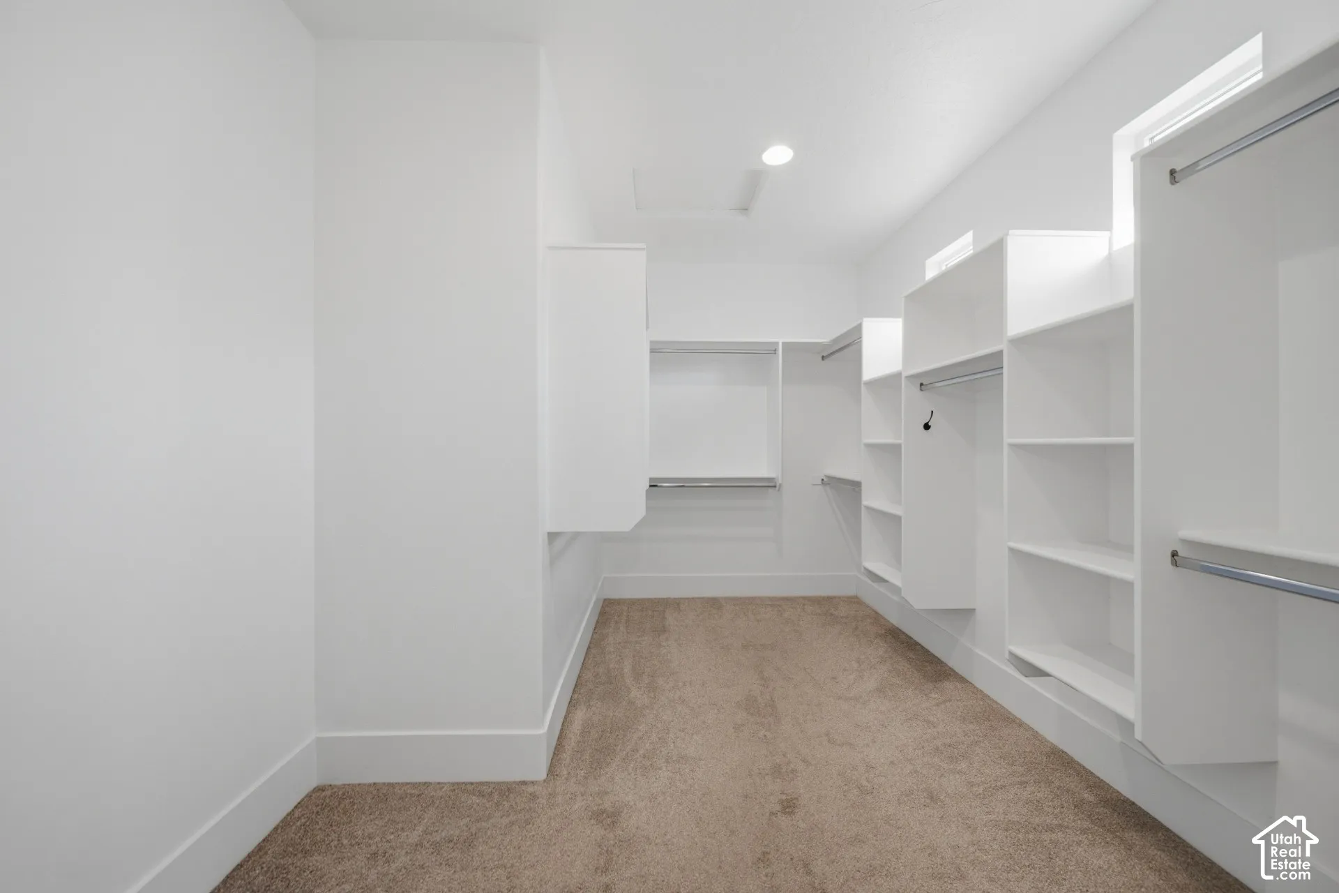 Expansive closet featuring built-in white shelving, integrated hanging rods, recessed lighting, and soft carpet flooring