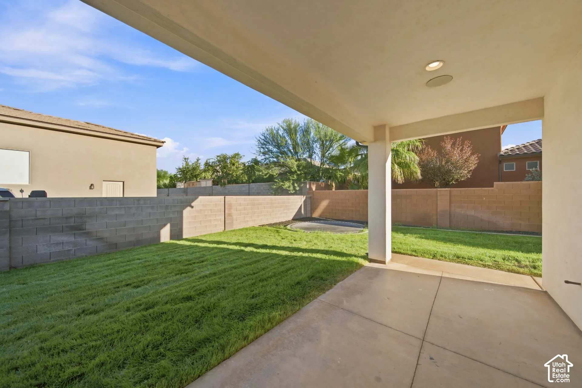 Covered patio with recessed lighting, integrated ceiling speaker, concrete flooring, and a grass lawn beyond