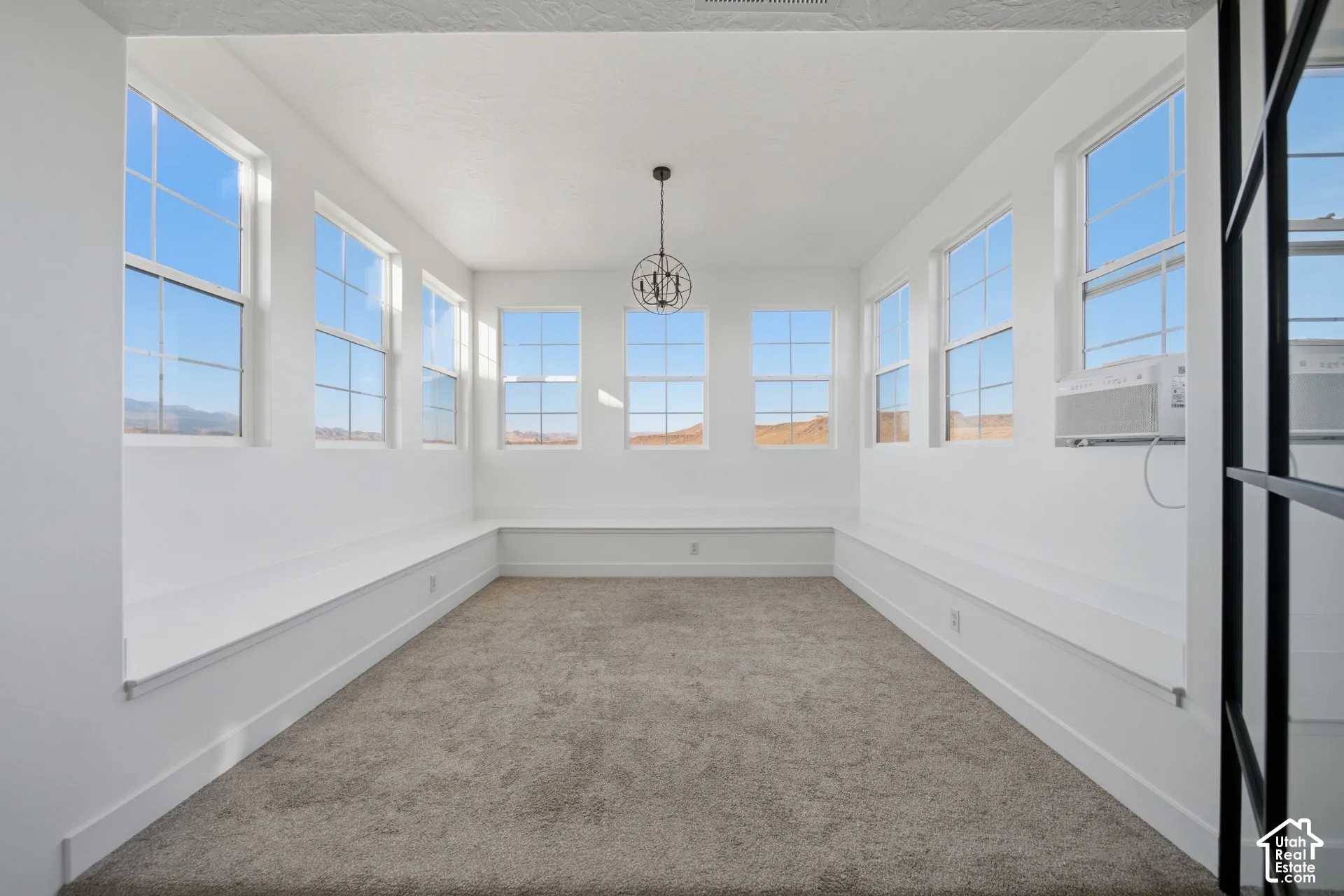 Bright interior featuring abundant windows, neutral carpeting, and a decorative chandelier
