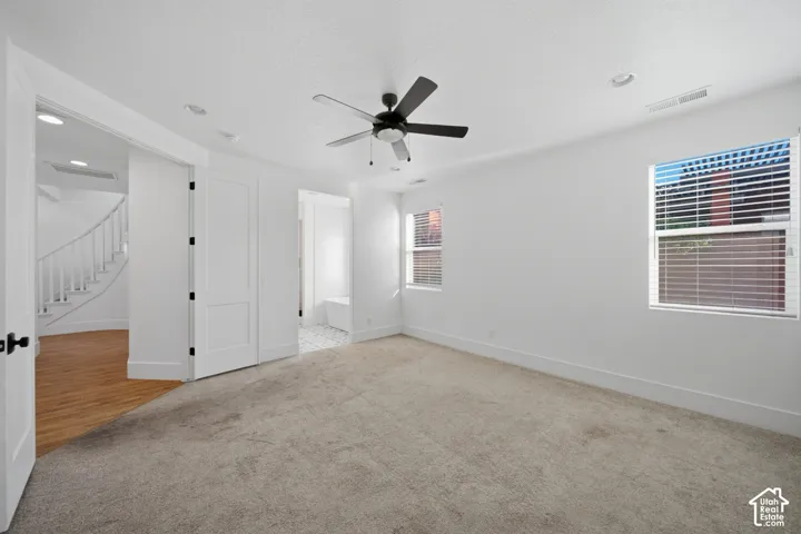 Carpeted room featuring two windows with blinds, a ceiling fan, and recessed lighting