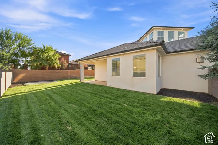 Expansive green lawn with a covered patio area and mature landscaping