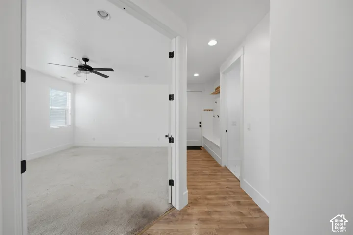 Recessed lighting illuminates the hallway with wood-finish flooring