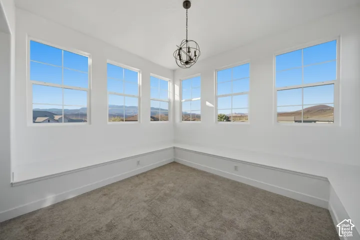 Multiple large windows, neutral-toned carpeting, built-in bench seating, and a decorative ceiling light fixture