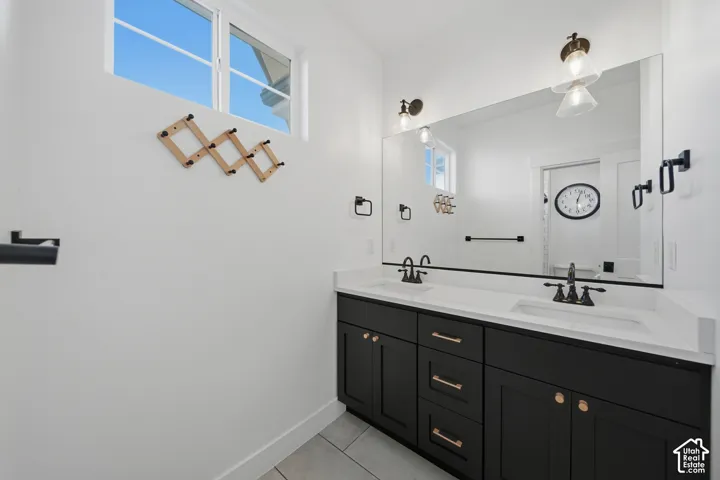 Dual vanity with black cabinetry and bronze hardware, featuring a large wall-mounted mirror and two sets of sconce lighting