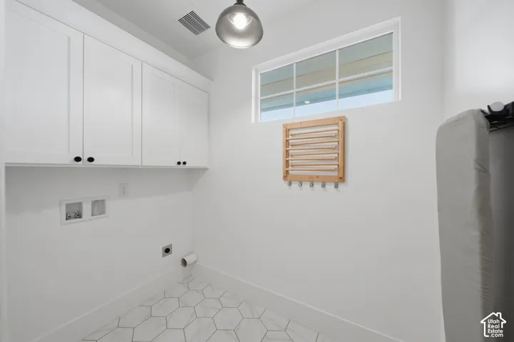 White shaker-style cabinetry with black hardware, hexagonal floor tiling, and a transom window