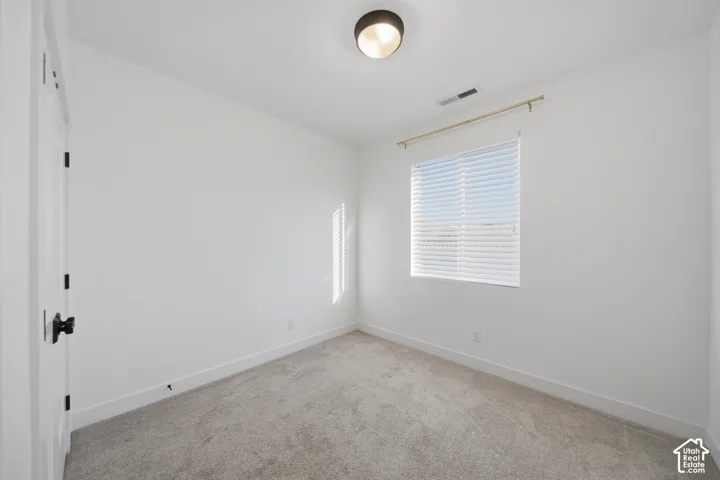 Plush carpet flooring, white walls, and a window with blinds