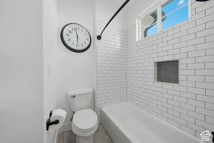 Bathtub with subway tile surround, recessed shower niche with penny tile, and an integrated window