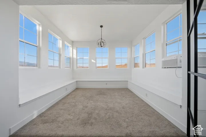 Bright interior featuring abundant windows, neutral carpeting, and a decorative chandelier