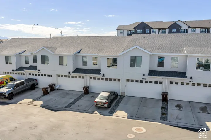 White exterior facade with multiple windows, individual garages, and concrete driveways