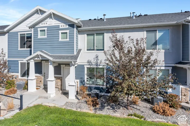 Townhouse exterior featuring a combination of blue siding and stucco, gabled rooflines, and a covered entryway with stone accents