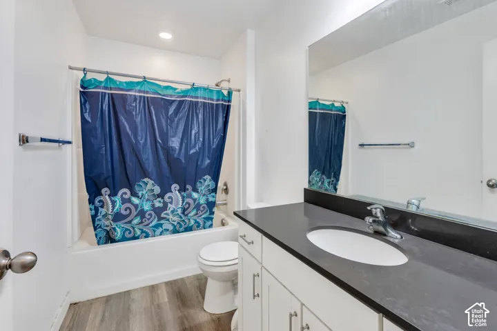 Bathroom featuring a white bathtub, toilet, and a vanity with a dark countertop and integrated sink