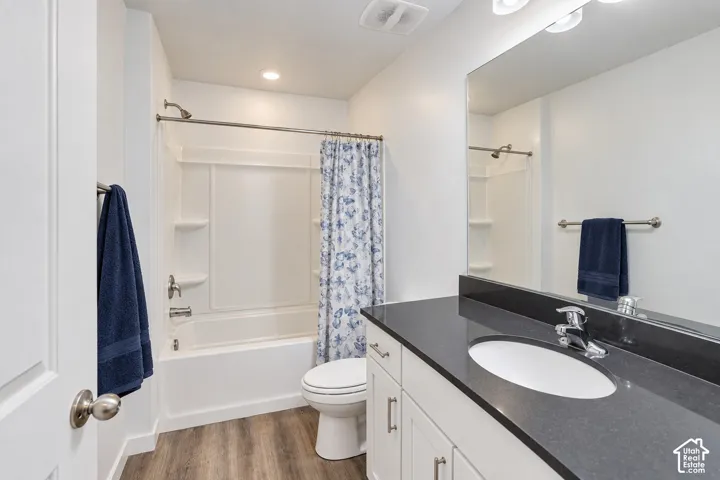 White vanity with a dark countertop, an oval undermount sink, and chrome fixtures