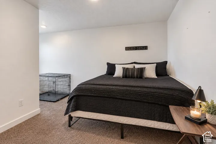 Plush carpet flooring, recessed ceiling lighting, and crisp white walls create a neutral palette