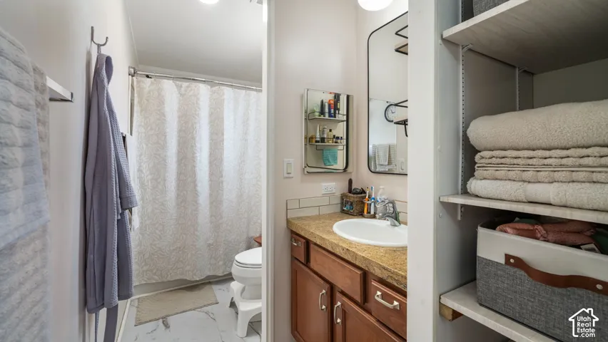 Bathroom featuring a vanity with a white basin, warm-toned countertop, wood-finish cabinetry, and a framed mirror