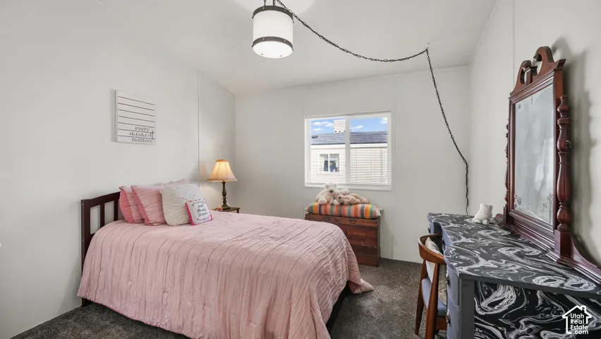 Recessed window with white trim, dark wood-finish bed frame, textured carpeting, and a ceiling-mounted light fixture