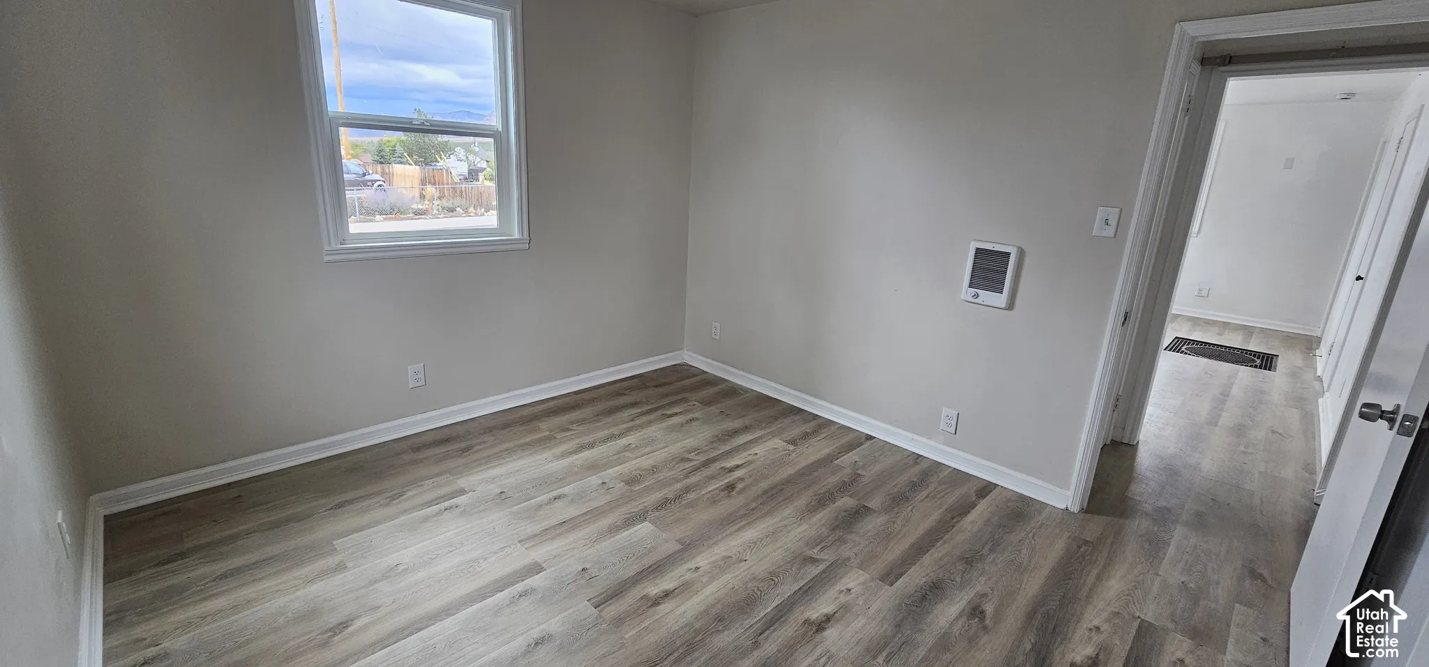 Wood-finish flooring, white trim, and a window with white casing