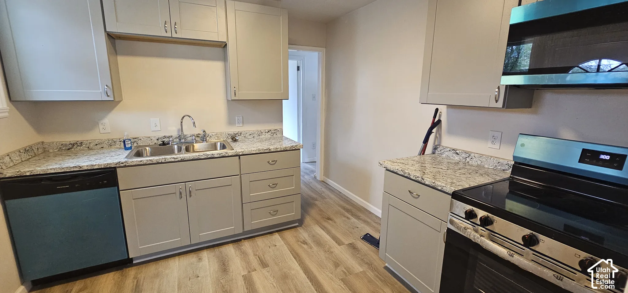 Kitchen featuring wood-finish flooring, light-toned cabinetry, granite countertops, and stainless-steel appliances