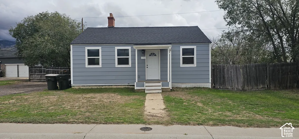 Gray siding exterior with white trim, dark shingle roof, and a red brick chimney