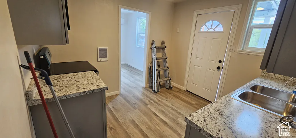 Kitchen featuring wood-finish flooring, granite-style countertops, stainless steel double basin sink, and gray cabinetry