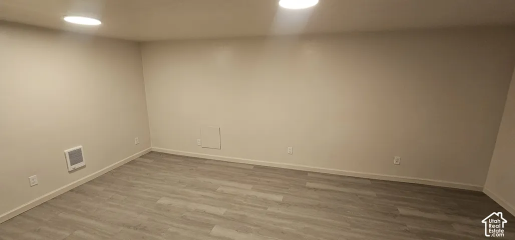 Recessed lighting illuminates neutral-toned walls and wood-finish flooring