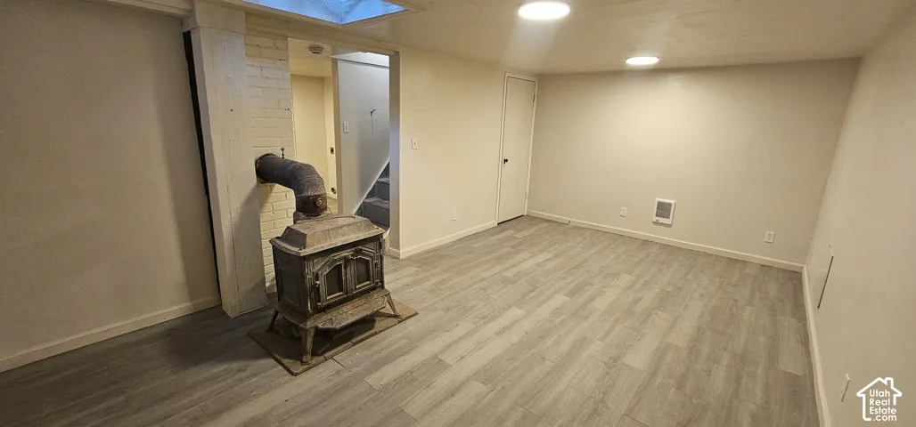 Spacious room with wood-finish flooring, recessed lighting, and a skylight