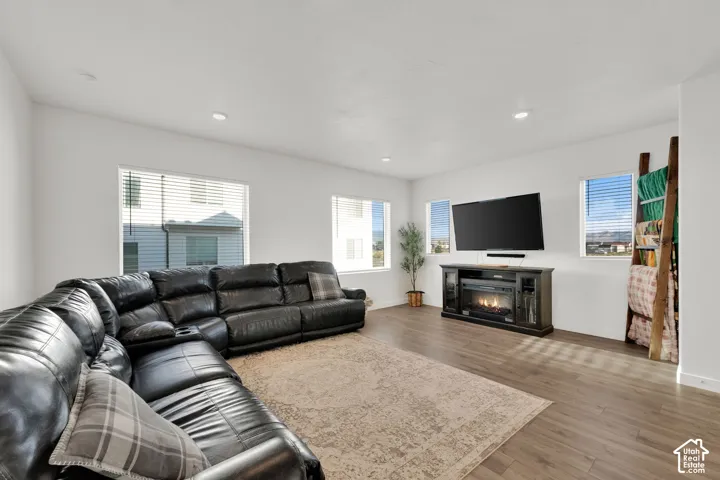 Spacious living area featuring wood-finish flooring, recessed lighting, and multiple windows with blinds