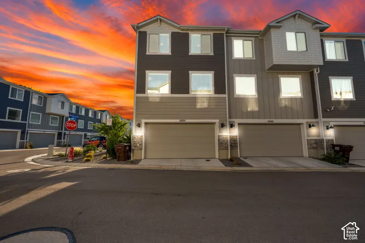 Contemporary townhome exterior with mixed siding, stone accents, and an integrated garage