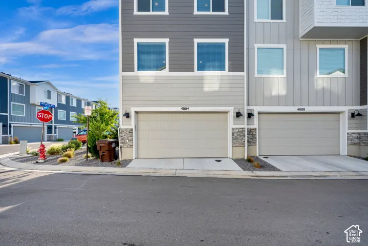 Multi-level exterior with horizontal and vertical siding, stone accents, white-framed windows, and integrated garage doors
