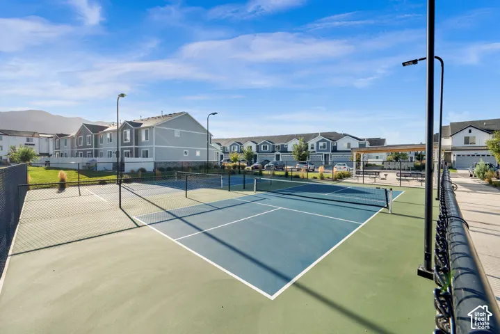 Outdoor recreation area featuring a tennis court, a pickleball court, and a covered seating area