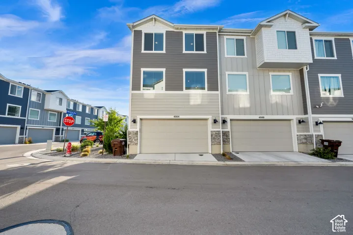 Multi-level townhome with an attached garage, modern siding, and a stone accent facade
