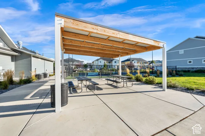 Covered outdoor seating area with picnic tables, adjacent to a court