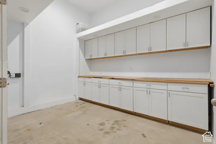 Extensive built-in cabinetry with white shaker-style doors, wood-finish countertops, and under-cabinet shelving