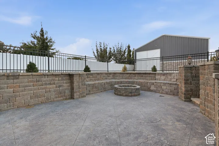 Stamped concrete patio with a built-in stone fire pit, surrounded by a stone retaining wall with integrated seating