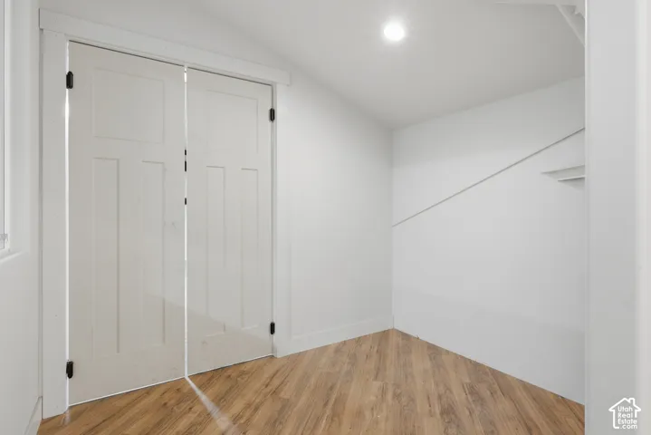 Wood-finish flooring, white paneled doors with dark hardware, recessed ceiling lighting, and white wall finishes