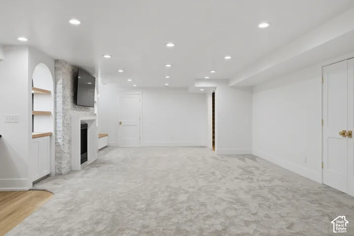 Recessed lighting, built-in fireplace, arched built-in shelving, wood-finish flooring, and light-toned carpeting