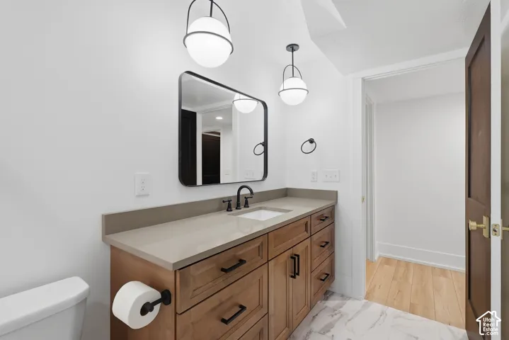 Vanity with wood-finish cabinetry, light-colored countertop, undermount sink, and matte black faucet