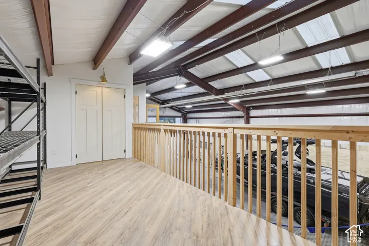 Upper-level mezzanine featuring wood-finish flooring, a natural wood railing, and white bi-fold doors