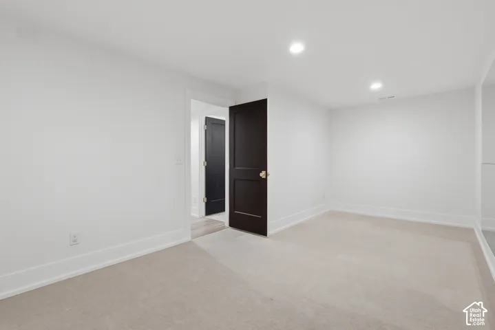 Recessed lighting illuminates the neutral-toned carpeted flooring and white walls