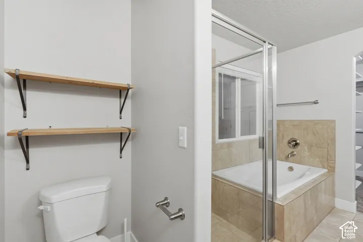 Built-in corner bathtub, glass shower enclosure, and two wall-mounted wooden shelves