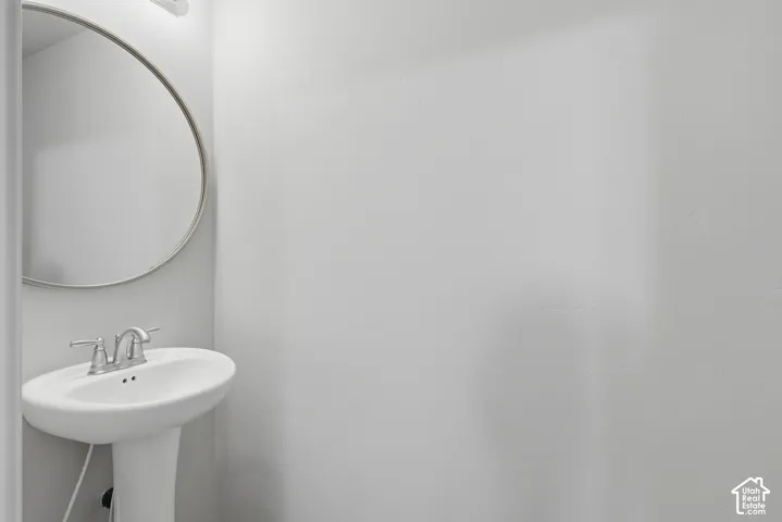 Pedestal sink with chrome-finish faucet and a round wall-mounted mirror