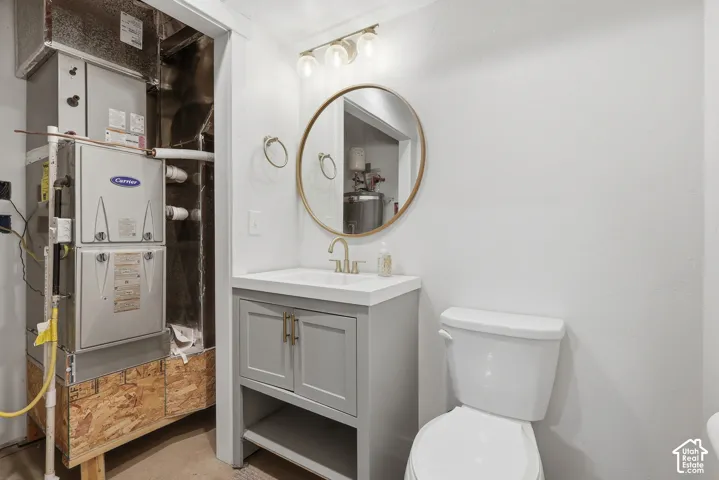 White vanity with a single basin sink, gold-finish faucet, and round mirror