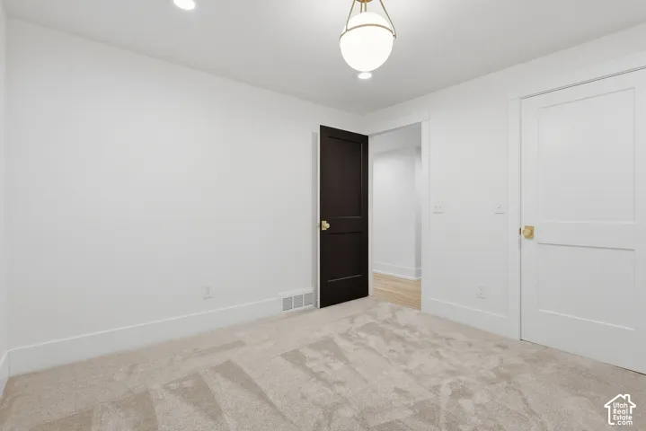 Neutral-toned carpeting, recessed ceiling lighting, and a modern globe pendant light fixture